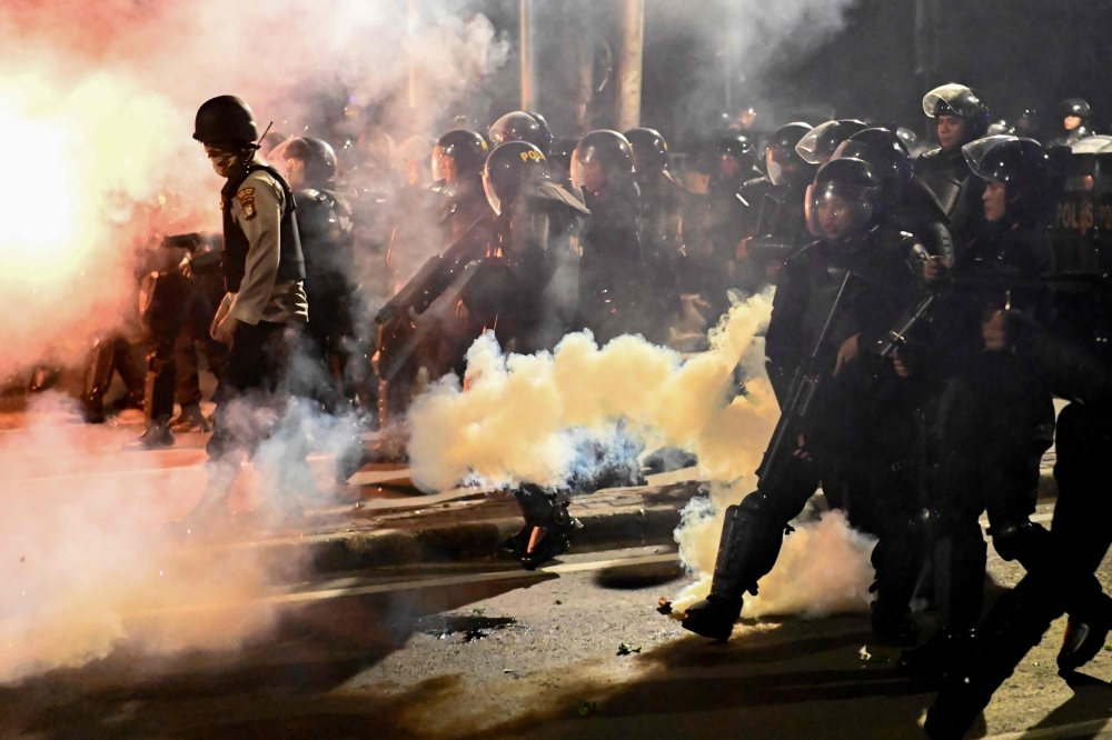 Indonesian police shoot tear gas to disperse protesters during a demonstration outside the Elections Oversight Body (Bawaslu) in Jakarta on Wednesday. Heavily armed Indonesian troops were on high alert amid fears of civil unrest in the capital Jakarta, as the surprise early announcement of official election results handed Joko Widodo another term as leader of the world's third-biggest democracy. — AFP