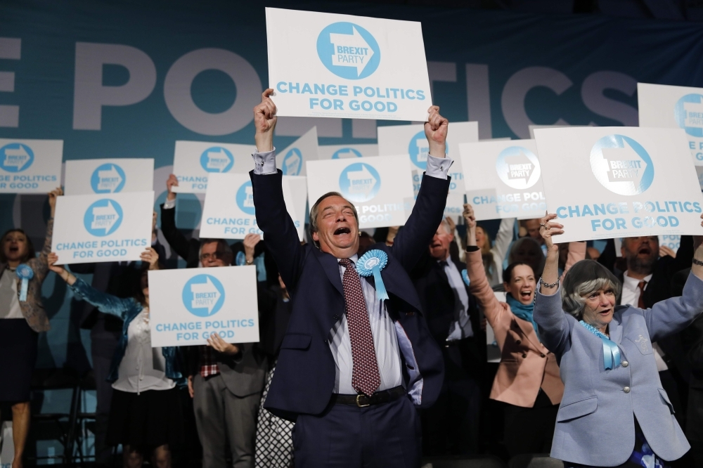 Brexit Party leader Nigel Farage (C) holds up a placard at the end of a European Parliament election campaign rally at Olympia London,  west London on Tuesday. — AFP