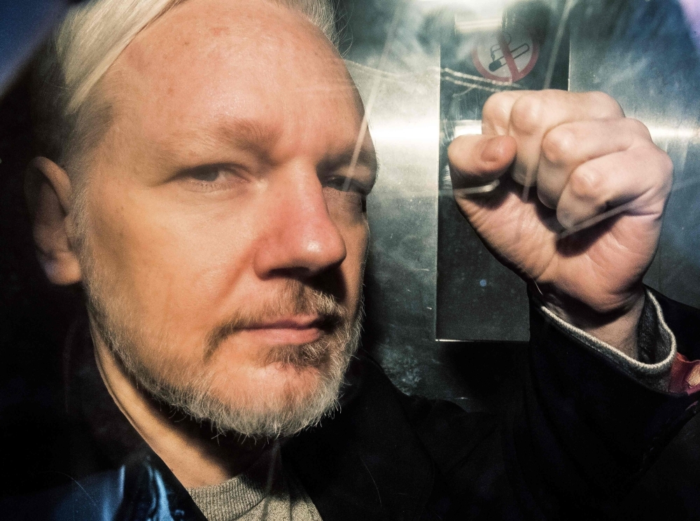 WikiLeaks founder Julian Assange gestures from the window of a prison van as he is driven into Southwark Crown Court in London, before being sentenced to 50 weeks in prison for breaching his bail conditions in 2012, in this May 1, 2019 file photo. — AFP