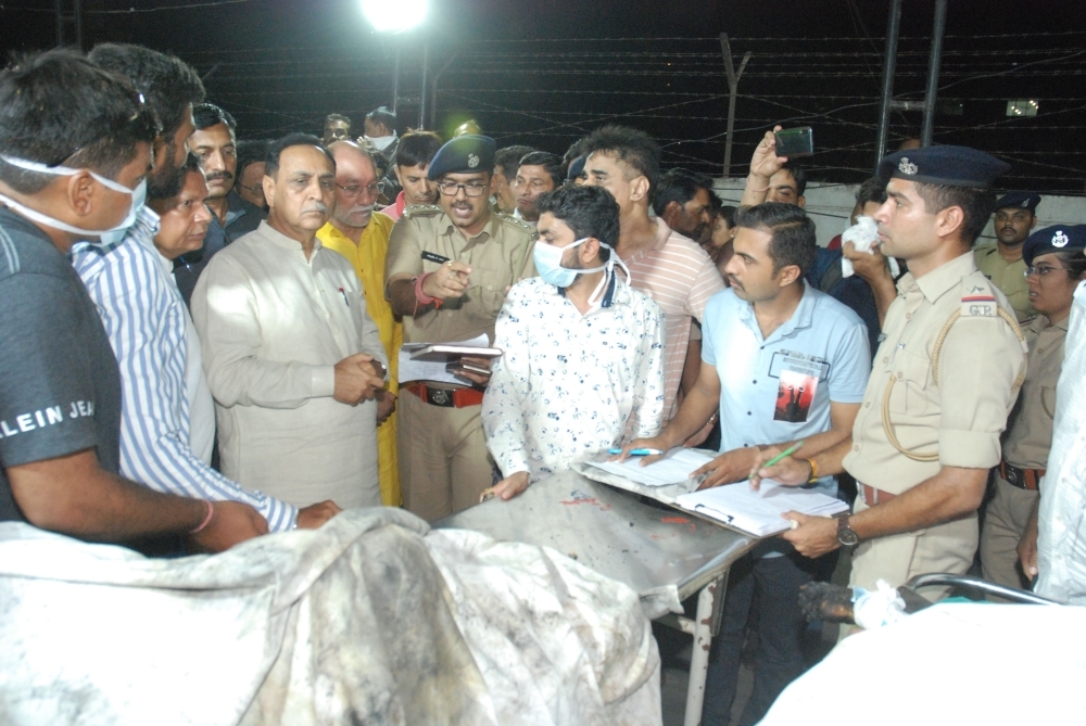 In this picture taken on Friday, Gujarat Chief Minister Vijaybhai Rupani (3 left) stand near the bodies of students, who died in a fire in a building in India housing a college, at a hospital in Surat, some 270 km, from Ahmedabad. — AFP
