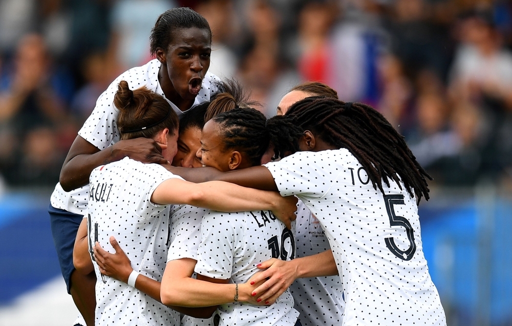 France's midfielder Elise Bussaglia, hidden, is congratulated by teammates after scoring a goal during the friendly football match between France and Thailand at La Source stadium in Orleans, France, on Saturday. — AFP