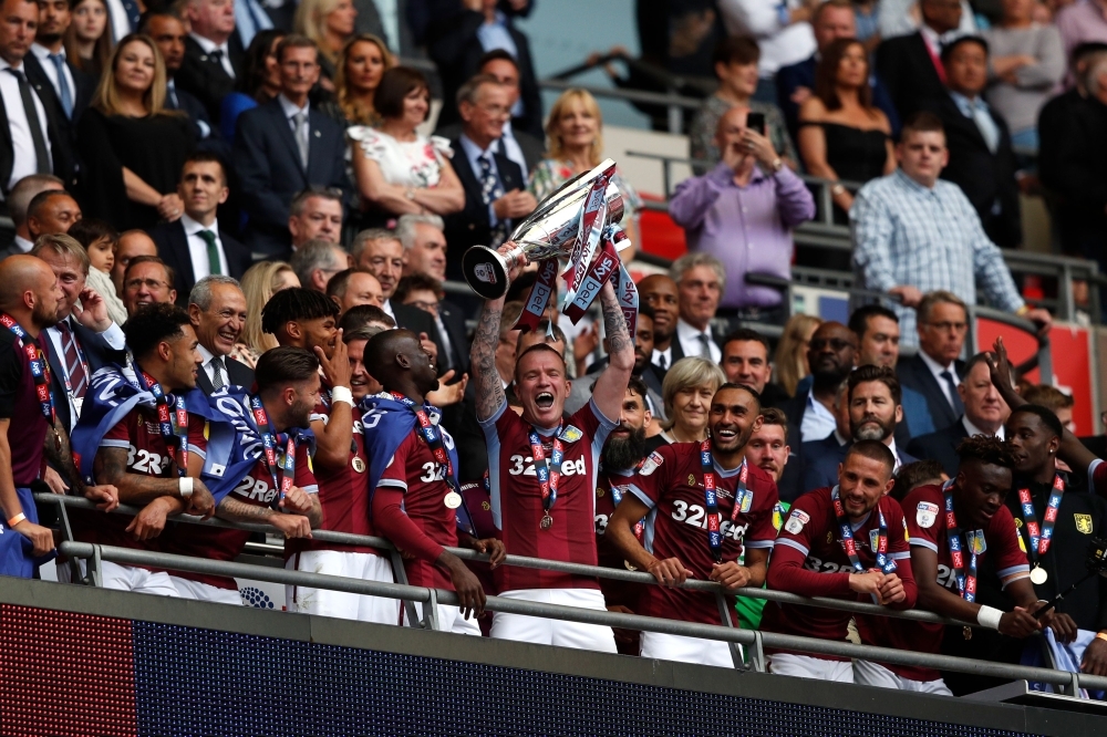 Aston Villa's Mile Jedinak and assistant manager John Terry celebrate with the trophy after winning the playoffs against Derby County at the Wembley Stadium, London, Britain, on Monday. — Reuters