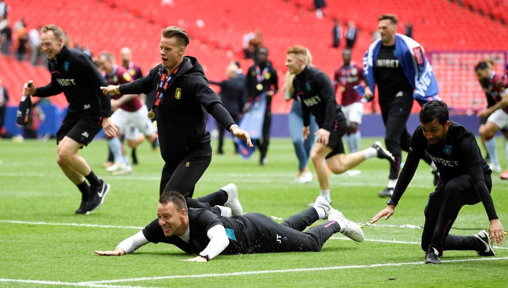 Aston Villa's Mile Jedinak and assistant manager John Terry celebrate with the trophy after winning the playoffs against Derby County at the Wembley Stadium, London, Britain, on Monday. — Reuters