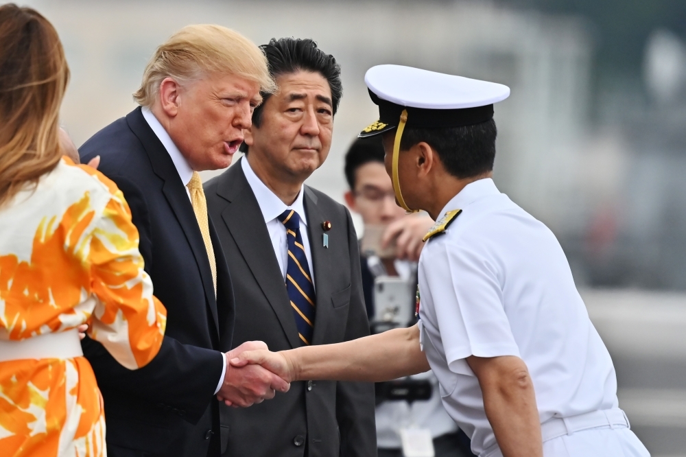 US President Donald Trump hands shakes captain Mizuta as First Lady Melania  and  Japan's Prime Minister Shinzo Abe look on onboard Japan's navy ship Kaga in Yokosuka on May 28. — AFP