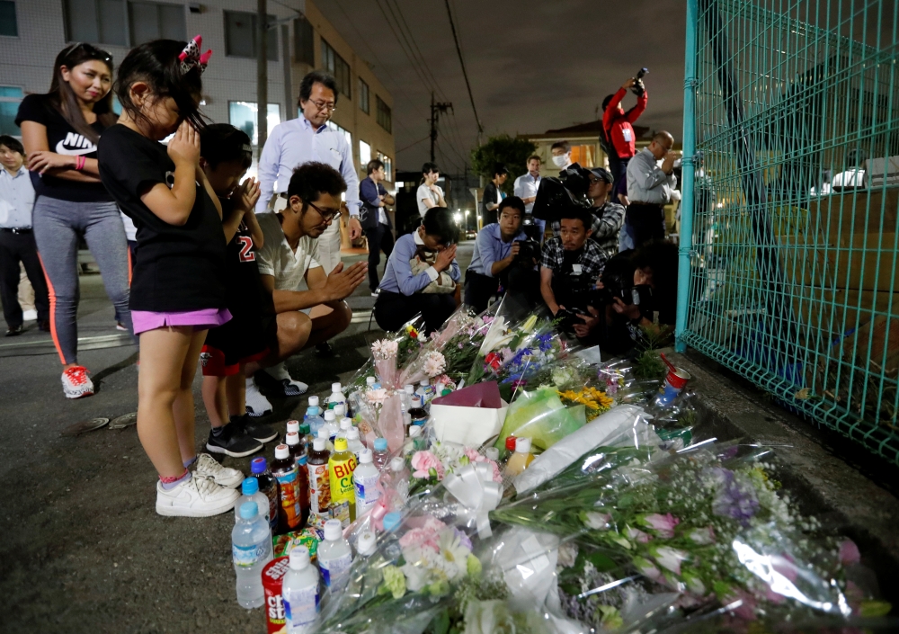 Local residents pray to mourn victims at the site where a stabbing occured in Kawasaki, Japan, on Tuesday.  — Reuters