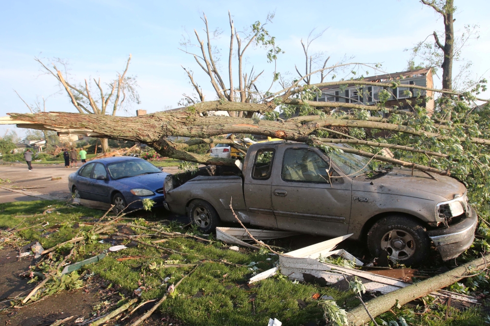 A car and truck sit under a fallen tree the morning after a tornado touched down overnight in Trotwood near Dayton, Ohio, US, on Tuesday. — Reuters