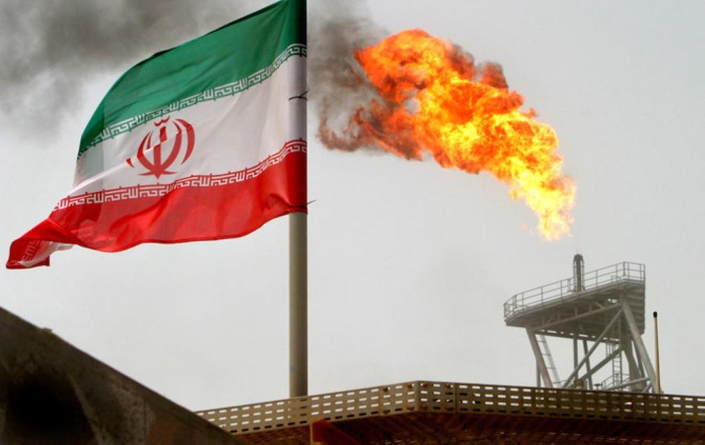 A gas flare on an oil production platform in the Soroush oil fields is seen alongside an Iranian flag in the Arabian Gulf. — File photo