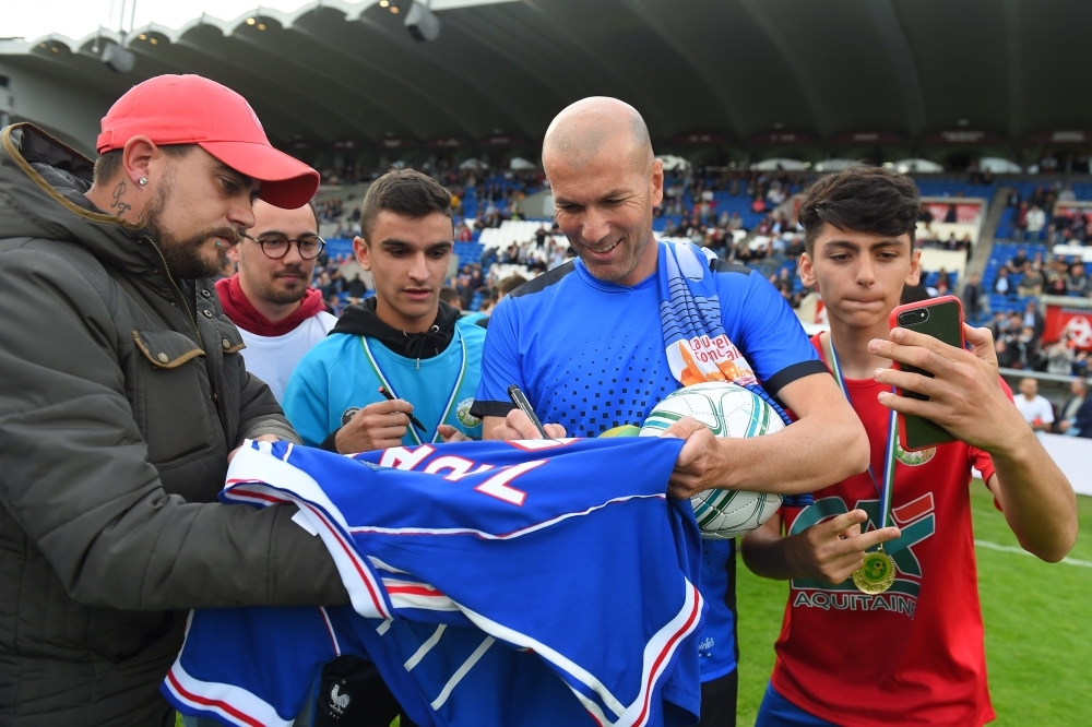 Real Madrid French coach Zinedine Zidane signs a jersey prior to a friendly football and rugby union match between former French football stars and former French rugby players. — AFP