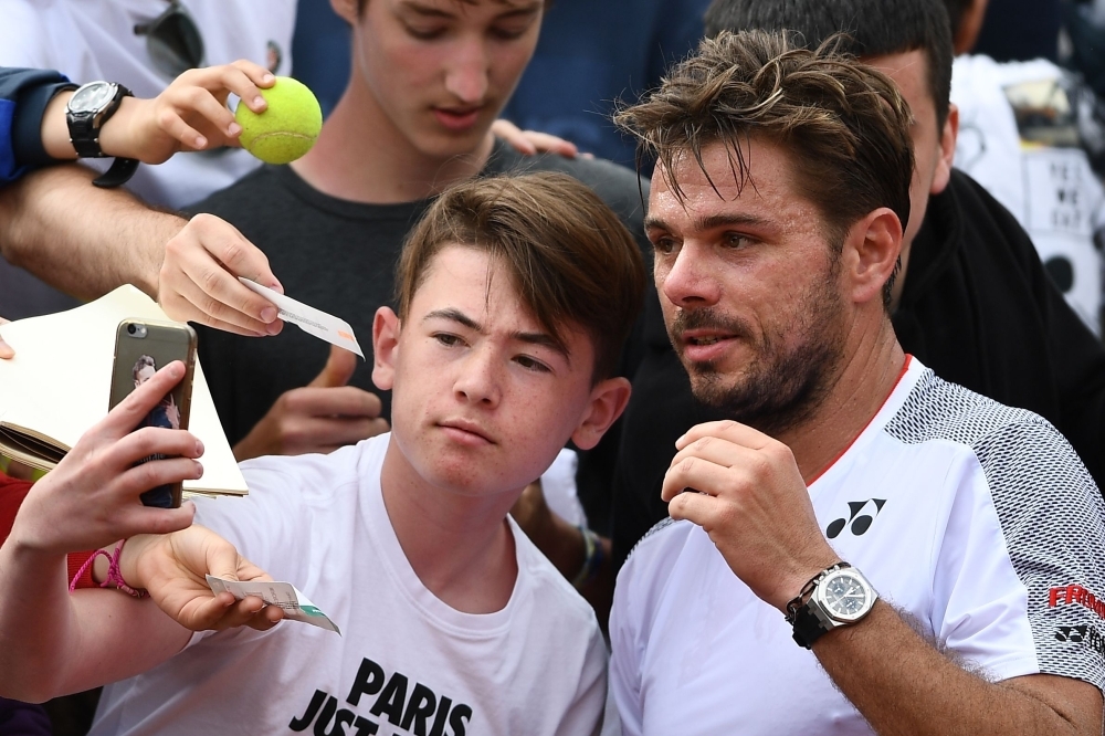 Switzerland's Stanislas Wawrinka poses for a selfie picture with a fan at the end of his men's singles second round match against Chile's Christian Garin on day four of The Roland Garros 2019 French Open tennis tournament in Paris on Wednesday. — AFP