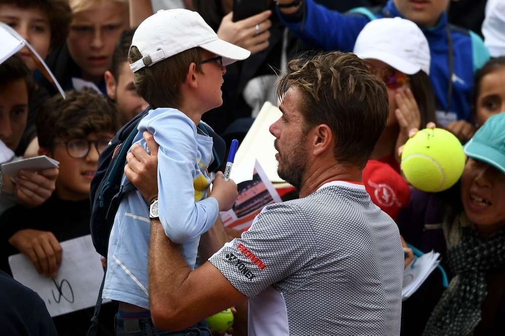 Switzerland's Stanislas Wawrinka poses for a selfie picture with a fan at the end of his men's singles second round match against Chile's Christian Garin on day four of The Roland Garros 2019 French Open tennis tournament in Paris on Wednesday. — AFP