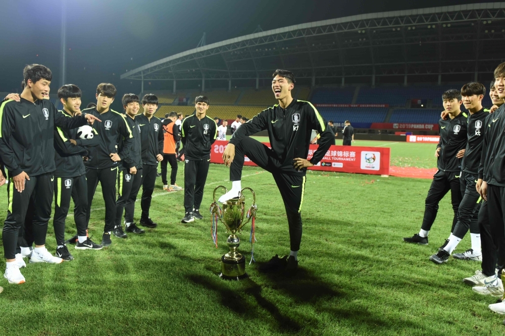 A handout picture from Osports taken on Wednesday and released on Thursday shows a member of South Korea youth team of under-18 squad posing for a picture with his foot on the trophy after winning the youth international competition in Chengdu, China's Sichuan province. South Korea's victorious under-18 footballers apologized to 