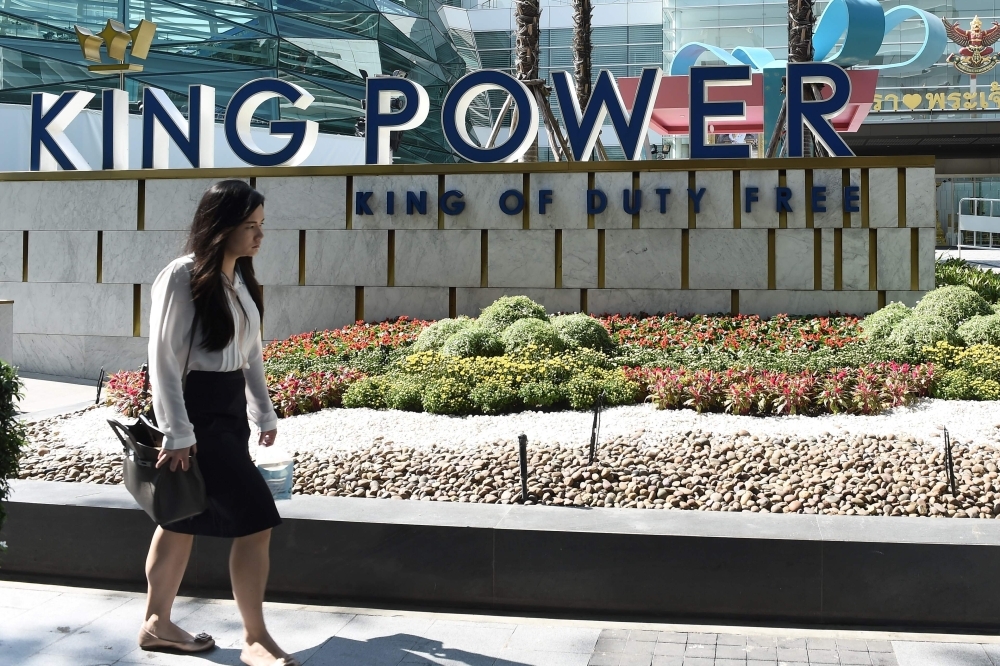 In this file photo a woman walks past the facade of the late Vichai Srivaddhanaprabha's duty-free business empire King Power in Bangkok. Thailand's King Power won the auction to run duty-free in Bangkok's biggest airport, state-owned Airports of Thailand announced Friday, priming the company to extend its monopoly over a concession worth nearly $2 billion a year. — AFP