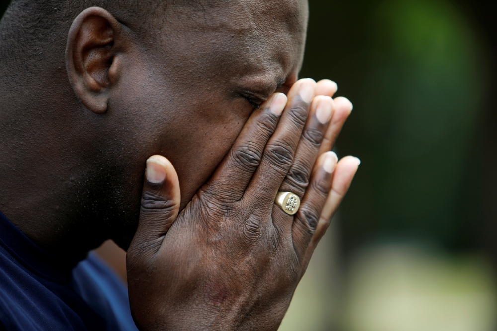 A local resident wipes away tears while praying with other members of his church near a municipal government building where a shooting incident occurred in Virginia Beach, Virginia, Saturday.  — Reuters