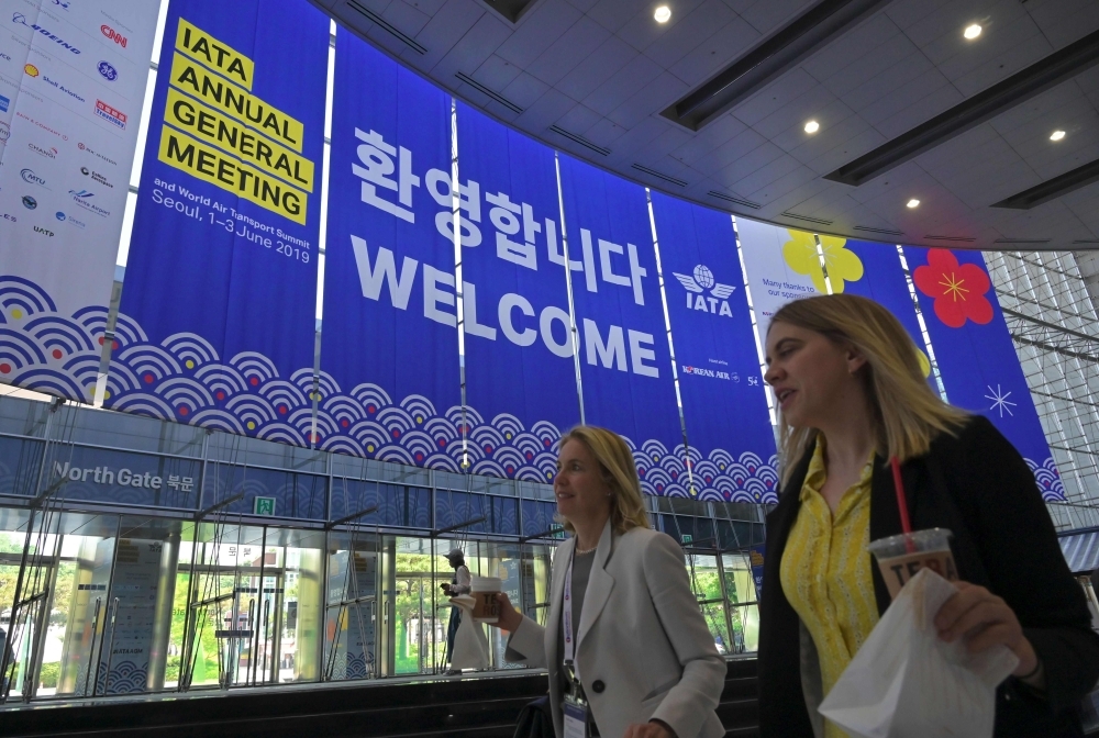 People walk past IATA banners during the annual general meeting of International Air Transport Association (IATA) at COEX convention and exhibition center in Seoul on Sunday. — AFP