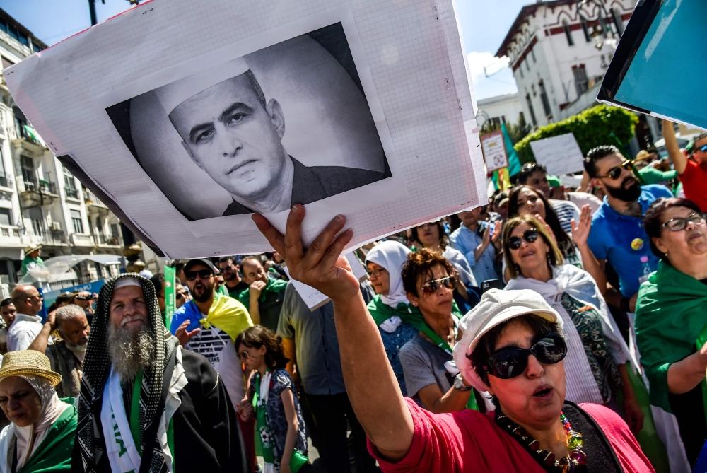 An Algerian protester marches with a sign showing the portrait of political activist Kamel Eddine Fekhar, who died days earlier, during a demonstration in the capital Algiers, on Sunday. — AFP