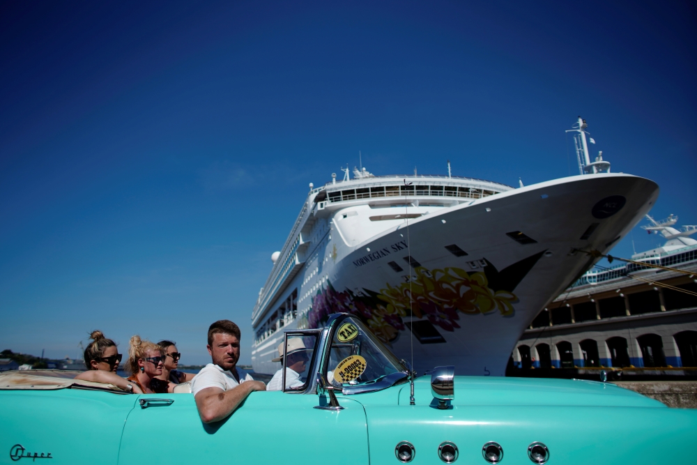 Tourists ride in a vintage car next to a cruise ship docked in Havana, Cuba, on Tuesday. — Reuters