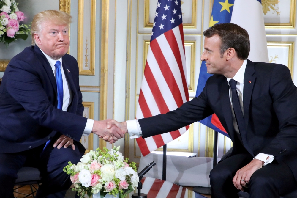 US President Donald Trump and French President Emmanuel Macron shake hands during a meeting in Caen, western France, on Thursday. — Reuters