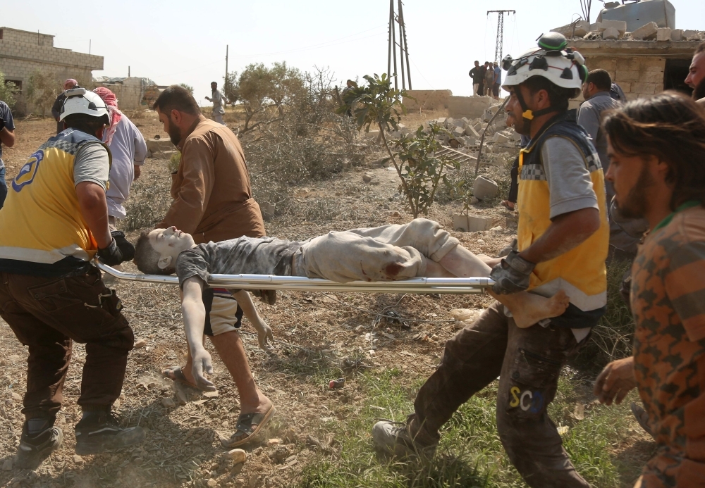 Members of the Syrian Civil Defence (known as the White Helmets) evacuate an injured boy following a reported air strike by pro-government forces on the village of Babuline near the town of Khan Shaykhun, in Idlib province on Friday. — AFP
