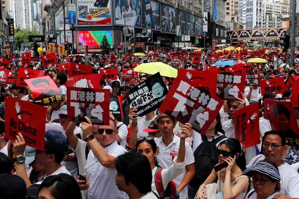 Demonstrators hold yellow umbrellas, the symbol of the Occupy Central movement, and placards during a protest to demand authorities scrap a proposed extradition bill with China, in Hong Kong, Sunday. — Reuters