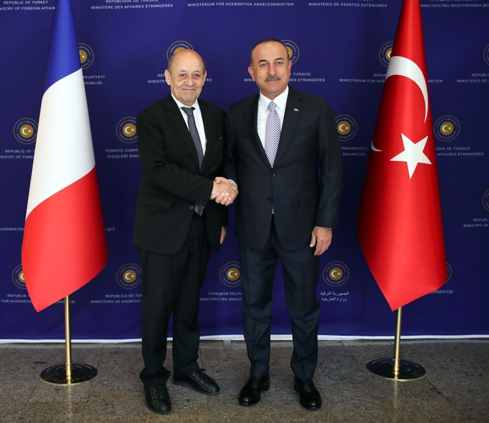 A handout photo shows Turkish Foreign Minister Mevlut Cavusoglu (R) shaking hands with his French counterpart Jean-Yves Le Drian (L) during their meeting in Ankara, on Thursday. — AFP