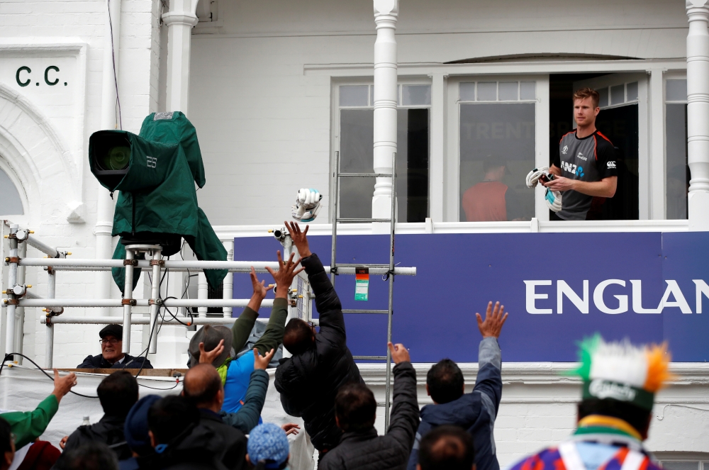 New Zealand's James Neesham throws his gloves to the fans during a rain delay during the ICC Cricket World Cup match against India at Trent Bridge, Nottingham, Britain, on Thursday. — Reuters