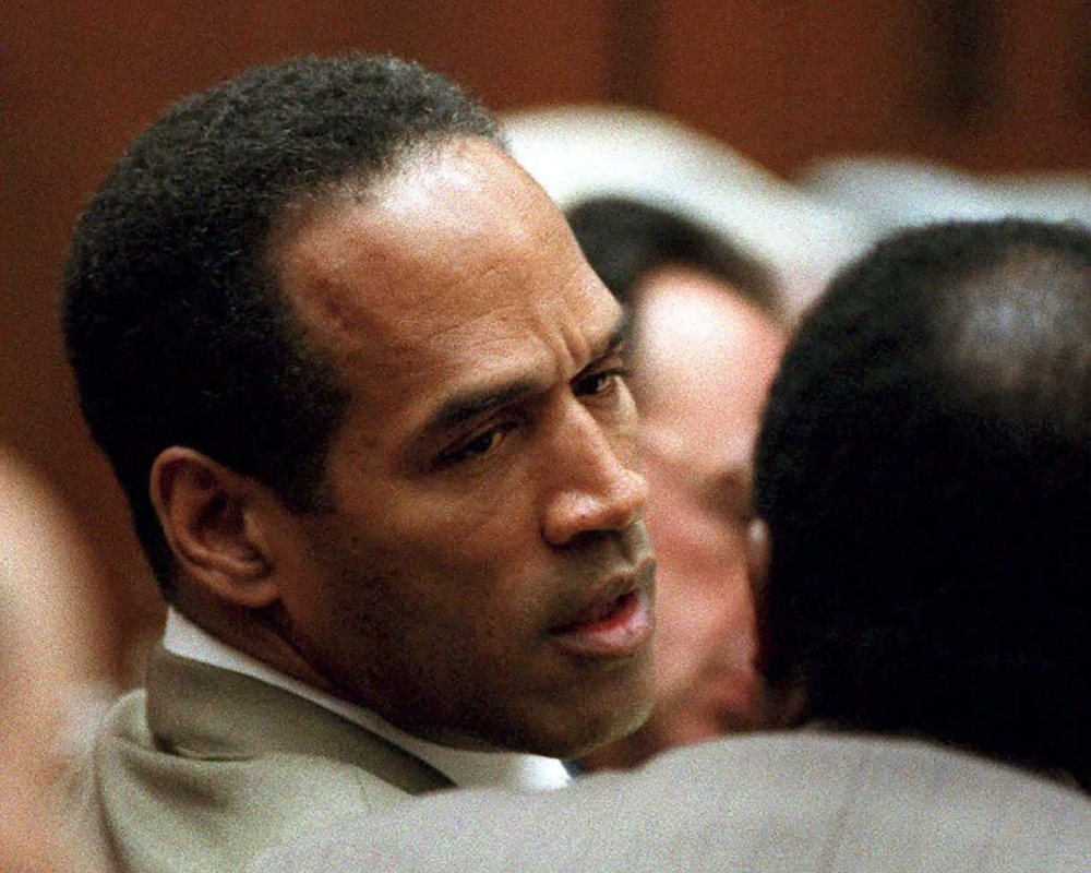 Double murder defendant O.J. Simpson, left, talks to attorney Johnnie Cochran Jr., during testimony by a Los Angeles Detective Ron Phillips in this Feb. 15, 1995 file photo. — AFP