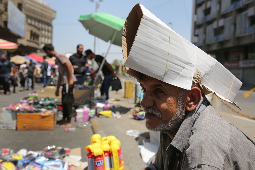 An Iraqi street vendor protects his head from the sun by using a piece of cardboard as a hat during a heat wave in the capital Baghdad in this June 14, 2019 file photo. — AFP