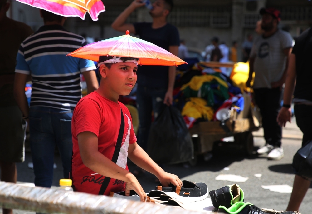 An Iraqi street vendor protects his head from the sun by using a piece of cardboard as a hat during a heat wave in the capital Baghdad in this June 14, 2019 file photo. — AFP