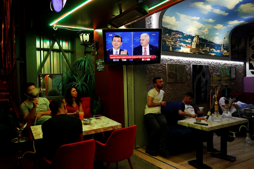 People watch a televised debate between Istanbul's mayoral candidates Ekrem Imamoglu of Republican People's Party (CHP) and Binali Yildirim of AK Party (AKP) at a cafe in central Istanbul, Turkey, June 16, 2019. REUTERS/Murad Sezer