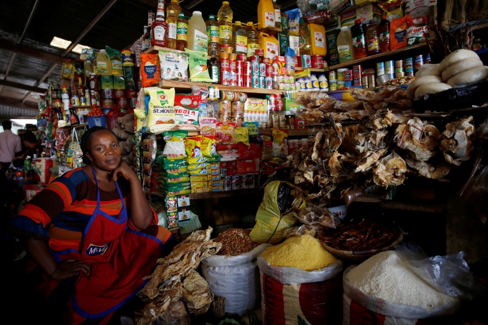 A woman sits near food items displayed for sale at a market in Abuja, Nigeria. — Reuters