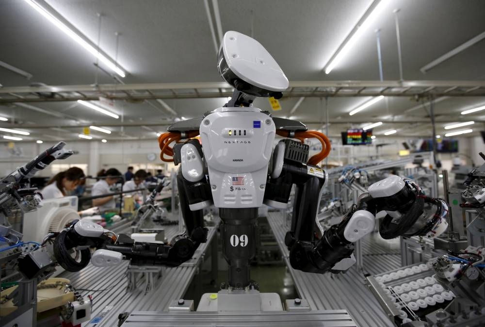 A humanoid robot works side by side with employees in the assembly line at a factory of Glory Ltd., a manufacturer of automatic change dispensers, in Kazo, north of Tokyo, Japan. — Reuters
