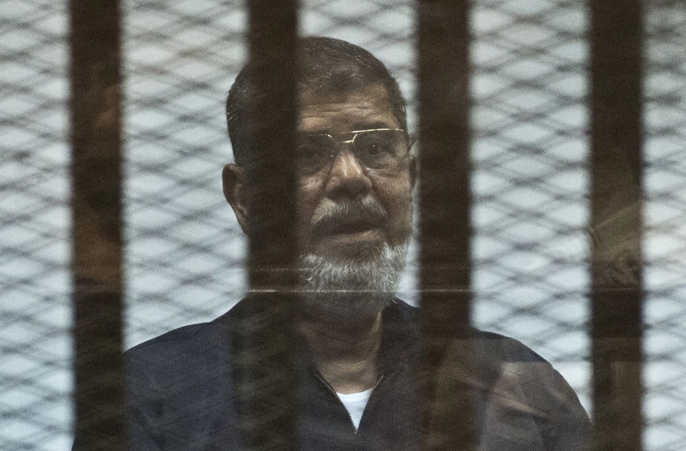 Egypt's former President Mohamed Morsi stands behind the bars during his trial in Cairo in this June 16, 2015 file photo. — AFP