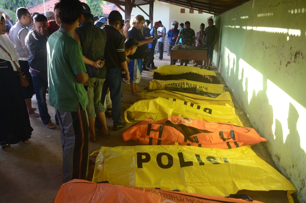 Indonesian villagers examine victims of a ferry accident in Dungkek, East Java, on Tuesday. — AFP