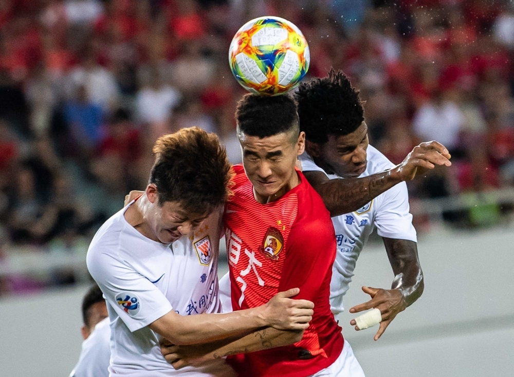 Wei Shihao (C) of Guangzhou Evergrande competes for the ball against Shandong Luneng players during their AFC Champions League Round of 16 football match in Guangzhou in China's southern Guangdong province on Tuesday. — AFP