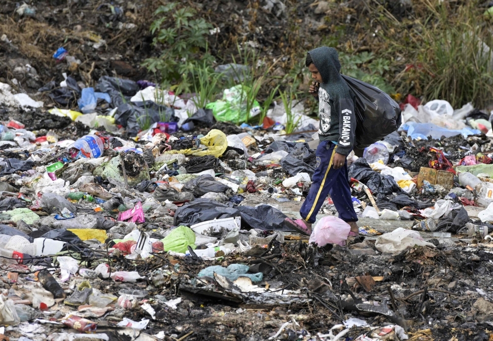A kid rummages in a garbage dump next to a highway in Jose Leon Suarez some 35 Km northwest of Buenos Aires, Argentina, in this May 31, 2019 file photo. — AFP