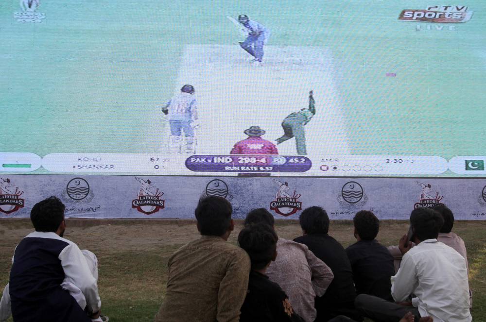 Pakistani cricket fans sit on the ground as they watch a screen displaying the ICC Cricket World Cup match between India and Pakistan in Manchester, at a park in Lahore, Pakistan on Sunday. — Reuter