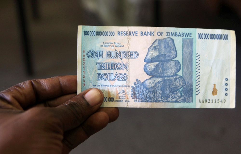 A man holds up for a picture a 100 trillion Zimbabwean dollar note inside a shop in Harare, Zimbawe. — File photo