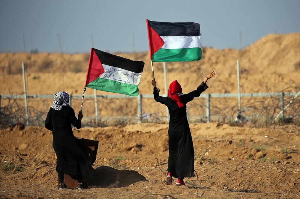 Women wave Palestinian flags during a protest at the Israel-Gaza border fence in the southern Gaza Strip. — Reuters