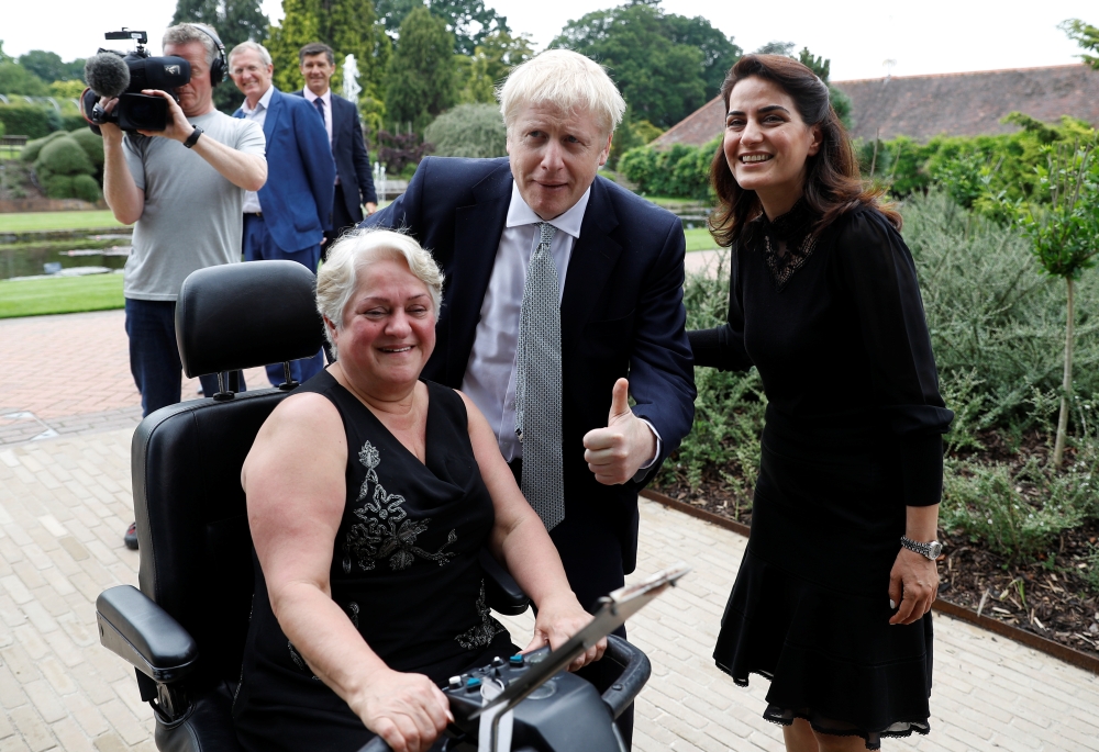 Boris Johnson, a leadership candidate for Britain's Conservative Party, poses with visitors during a walkabout at Wisley Garden Centre in Surrey, Britain, on Tuesday. — Reuters