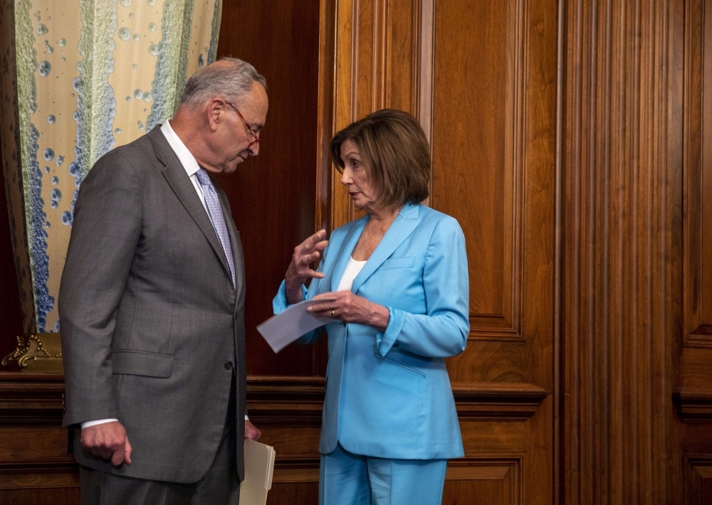 US Senate Minority Leader Chuck Schumer and US House Speaker Nancy Pelosi chat at a press conference on passing the America's Elections Act in Washington on Wednesday. — AFP