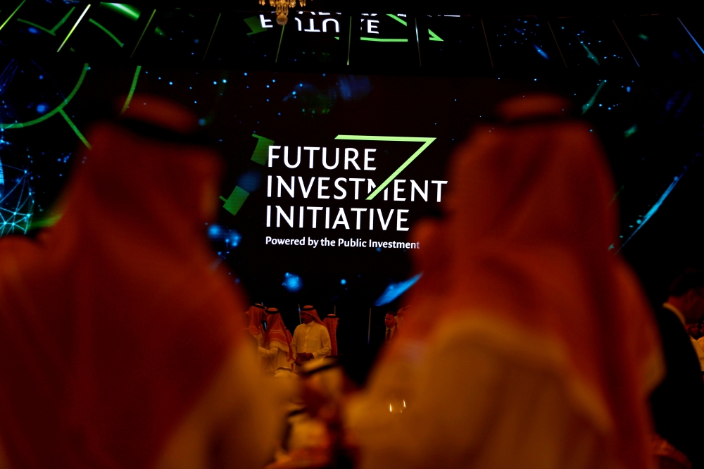 Participants look at a sign of the Future Investment Initiative during the investment conference in Riyadh, Saudi Arabia October 23, 2018.  REUTERS/FILE PHOTO