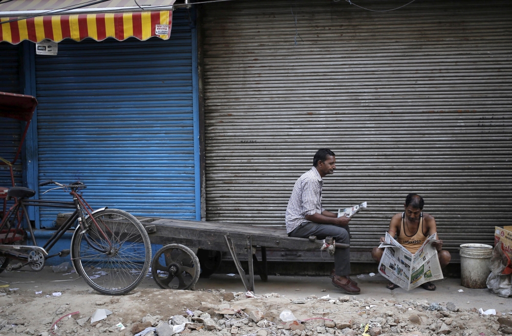 Laborers read newspapers in front of a closed shop in the old quarters of Delhi, India, in this March 29, 2016 file photo. — Reuters