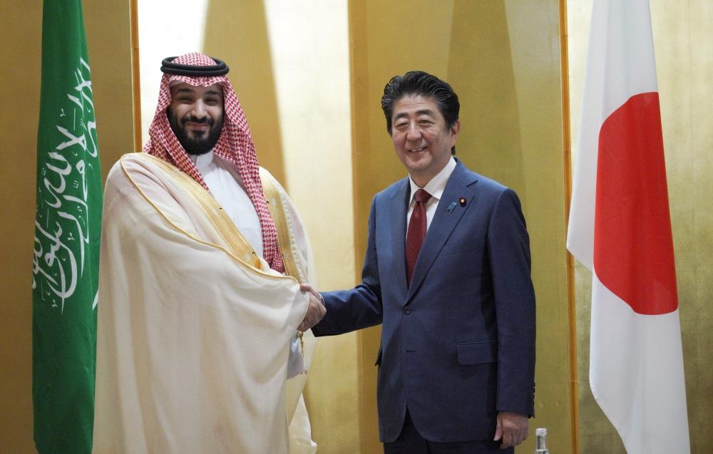 Crown Prince Muhammad Bin Salman and Japanese Prime Minister Shinzo Abe shake hands during their meeting in Osaka, western Japan Sunday. — Reuters