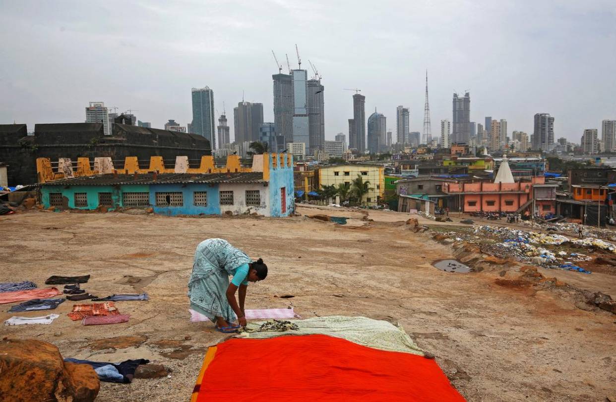 A woman puts clothes to dry overlooking central Mumbai's financial district skyline on June 18. -Reuters