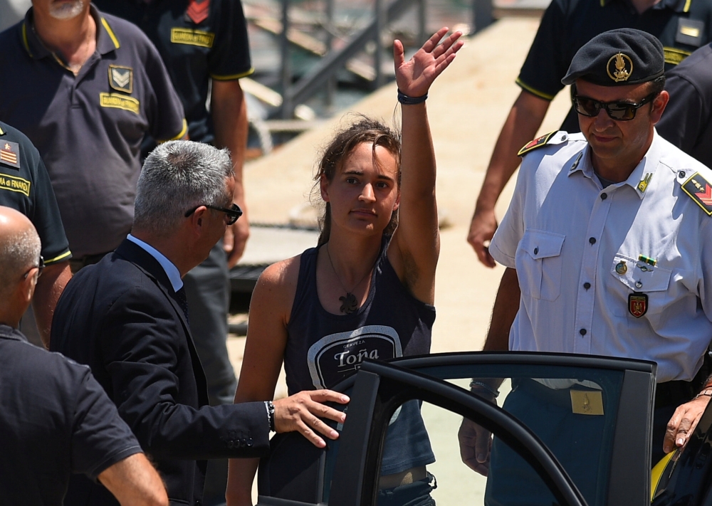 Carola Rackete, the 31-year-old Sea-Watch 3 captain, disembarks from a police boat and is escorted to a car, in Porto Empedocle, Italy, on Monday. — Reuters