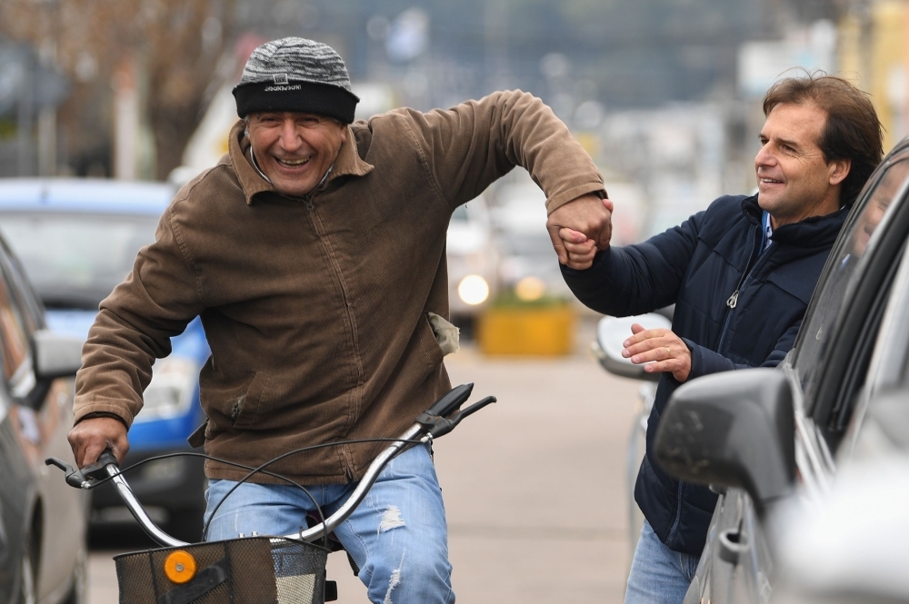 Uruguayan presidential pre-candidate of the National Party, Luis Lacalle Pou (R), is greeted by a supporter riding a bicycle as he arrives at the polling station to vote during the primary elections, in Canelones, Uruguay, on Sunday. — AFP