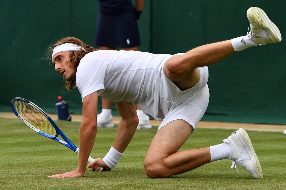 Greece's Stefanos Tsitsipas goes down as he returns against Italy's Thomas Fabbiano during their men's singles first round match on the first day of the 2019 Wimbledon Championships at The All England Lawn Tennis Club in Wimbledon, southwest London, on Monday. — AFP