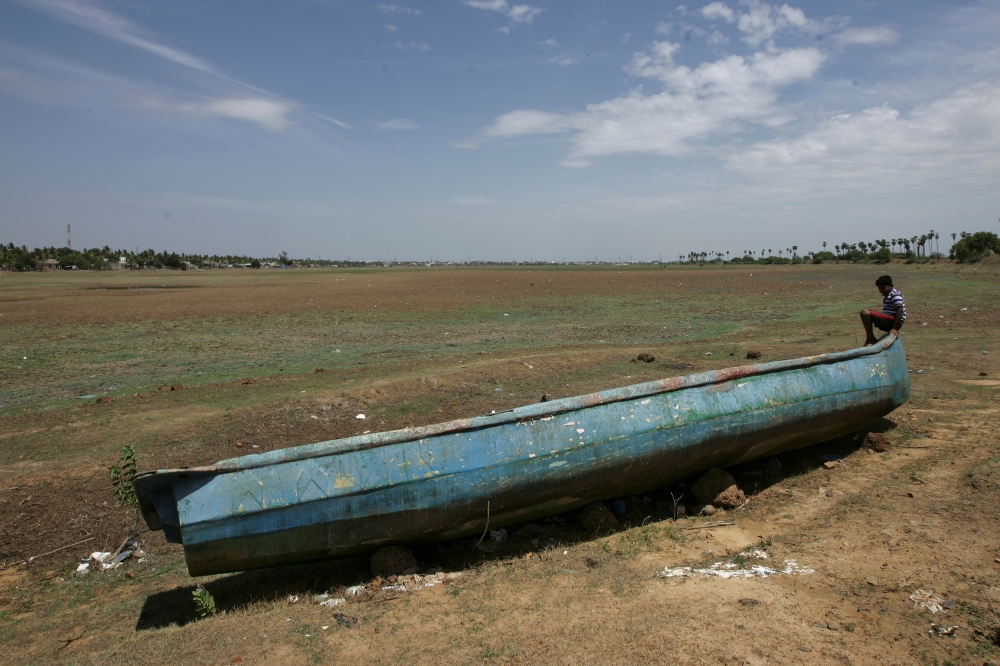 A man sits on a fishing boat stranded on the bed of dried-up lake in Thiruninravur, India, in this June 29, 2019 file photo. — Reuters