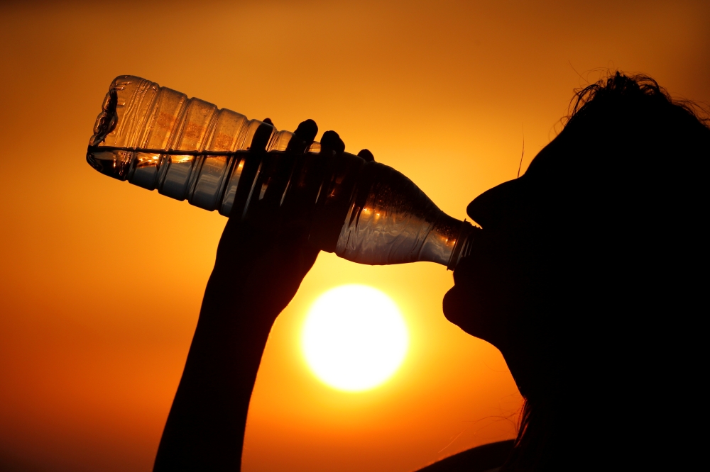 A woman drinks water during sunset, as a heat wave hits France, in Cagnicourt near Cambrai, France, in this June 25, 2019 file photo. — Reuters