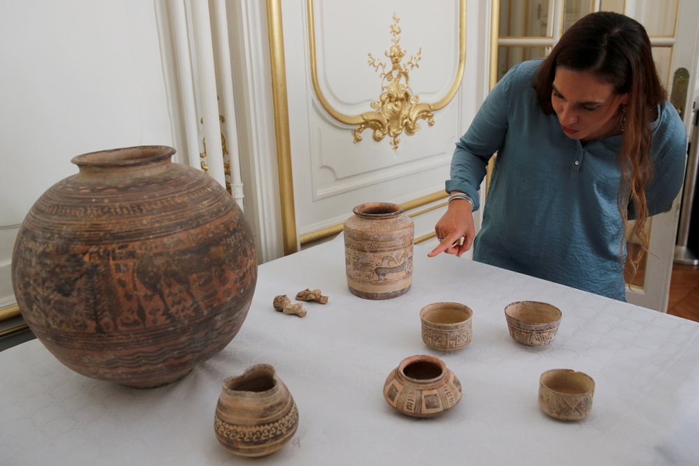 Archaeologist Aurore Didier points to some artifacts amongst the 445 artifacts from the 2nd and 3rd millennium BC which were seized by French customs between 2006 and 2007, before being returned by French authorities to Pakistan, during a ceremony at the Embassy of Pakistan in Paris, France, on Tuesday. — Reuters